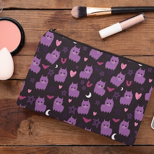 May include: Purple and black makeup bag with a repeating pattern of llamas, stars, hearts, and crescent moons.