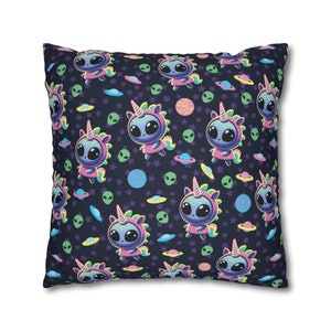 May include: A navy blue pillow with a repeating pattern of cute alien unicorns, stars, and planets. The unicorns are wearing pink and purple outfits and have rainbow manes.