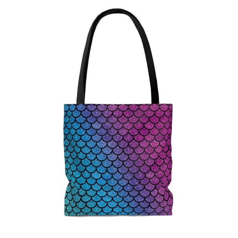 May include: A tote bag with a mermaid scale pattern. The scales are a gradient of pink, purple, blue, and teal. The bag has black straps.