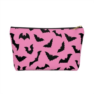 May include: Pink zippered pouch with a black bat pattern.
