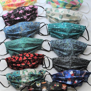 May include: A collection of 12 colorful fabric face masks with various patterns, including flamingos, pineapples, cacti, watermelon, and peacocks. The masks are pleated and have black elastic ear loops.