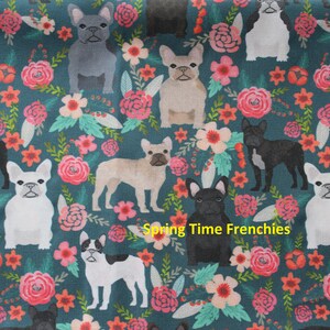 May include: Teal fabric with a repeating pattern of French bulldogs in various colors, interspersed with pink and coral flowers and green leaves. The text "Spring Time Frenchies" is in yellow.