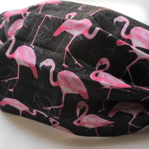 May include: Black face mask with a pink flamingo print. The mask has elastic ear loops.