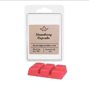 Puede incluir: Un paquete transparente que contiene un ambientador de cera con aroma a cupcake de fresa. La etiqueta dice "Strawberry Cupcake" y "Rockridgecandles.com". Debajo del paquete hay tres cubos de cera roja.