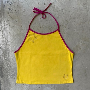 May include: Yellow halter top with a magenta trim and tie. The top features two rhinestone star designs. This sleeveless top is a vibrant piece of clothing.