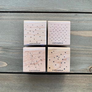 May include: A set of three ceramic mugs with a speckled, matte finish. Each mug features a different color: light blue, cream, and gray. The mugs have a simple, modern design and a comfortable handle.