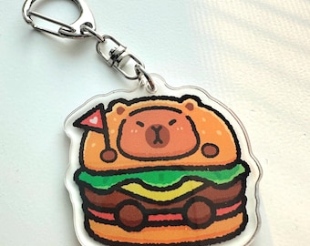 Könnte beinhalten: Ein brauner Bär, der einen roten und weißen Hut mit einem Herzen trägt, befindet sich in einem Cartoon-Burger. Der Burger hat Salat, Käse und eine Tomate. Das Bild ist auf einem durchsichtigen Acryl-Schlüsselanhänger.