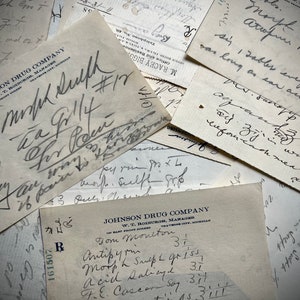 Puede incluir: Primer plano de varias recetas antiguas de Johnson Drug Company. Las recetas están escritas a mano con tinta negra e incluyen detalles como los nombres de los pacientes, los medicamentos y las dosis. Las recetas están apiladas unas sobre otras, creando un efecto de capas.