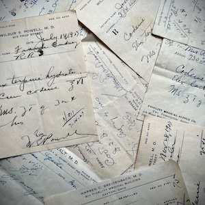 Op de afbeelding: Een verzameling vintage receptstrookjes met handgeschreven tekst, inclusief data, patiëntnamen en medicijninformatie. De strookjes zijn gestapeld en overlappen elkaar, waardoor een gelaagd effect ontstaat. De tekst is in zwarte inkt op wit papier.