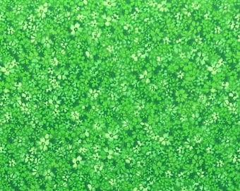 May include: Green fabric with a white floral pattern. The fabric is covered in small white flowers on a green background.