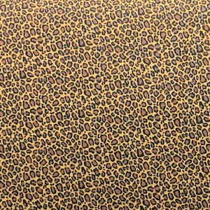 May include: A close-up of a yellow fabric with a brown leopard print pattern.