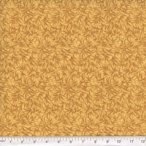 May include: A fabric with a repeating pattern of stylized, light brown leaves on a golden-yellow background. The leaves are detailed with darker brown veins, creating a textured appearance. The fabric is measured in inches.