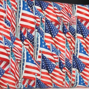 May include: A close-up of a fabric with a repeating pattern of American flags. The flags are red, white, and blue and are arranged in a diagonal pattern. The fabric is perfect for quilting, crafts, and other projects.