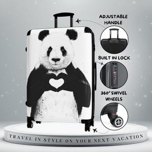 May include: A white suitcase with a black and white panda bear design, forming a heart shape with its paws. The luggage has an adjustable handle, built-in lock, and 360° swivel wheels. The text at the bottom reads: "TRAVEL IN STYLE ON YOUR NEXT VACATION."