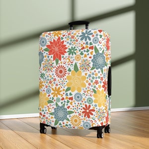 Peut inclure: Une housse de valise blanche avec un motif floral coloré. Le motif présente des fleurs rouges, jaunes, bleues et vertes sur un fond blanc.