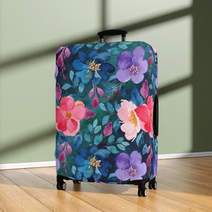 Peut inclure: Une housse de valise avec un motif floral. La housse présente des fleurs roses, bleues et violettes sur un fond vert foncé.