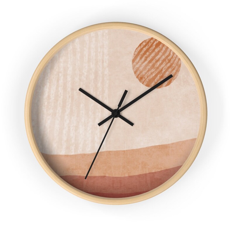 May include: A round wall clock with a beige background and a brown, striped circle in the upper right corner. The clock face has a minimalist design with black hands and a beige background.