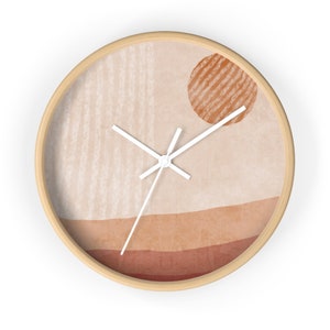 May include: A round wall clock with a wooden frame and a beige background. The clock face features a minimalist design with a sun-like shape in the top right corner and a horizontal line pattern in the bottom half. The clock hands are white.