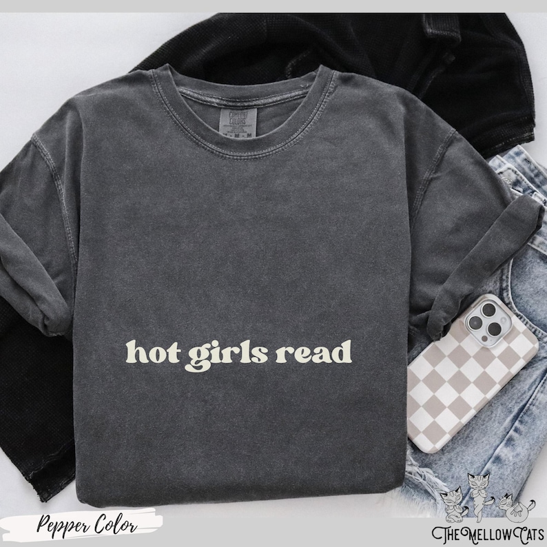 Puede incluir: Una camiseta gris oscuro con el texto "hot girls read" impreso en color amarillo claro.