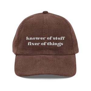 Può includere: Cappellino da baseball in velluto a coste marrone con la scritta bianca "knower of stuff fixer of things". Il cappellino ha una visiera curva e un bottone sulla parte superiore. Un bel regalo.