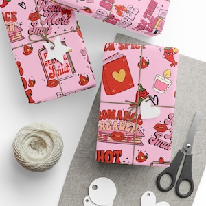 May include: Pink wrapping paper with a repeating pattern of lips, chili peppers, books, and the words "Read More Smut" and "Romance Reader". The wrapped gifts are tied with twine and adorned with heart-shaped and star-shaped tags.