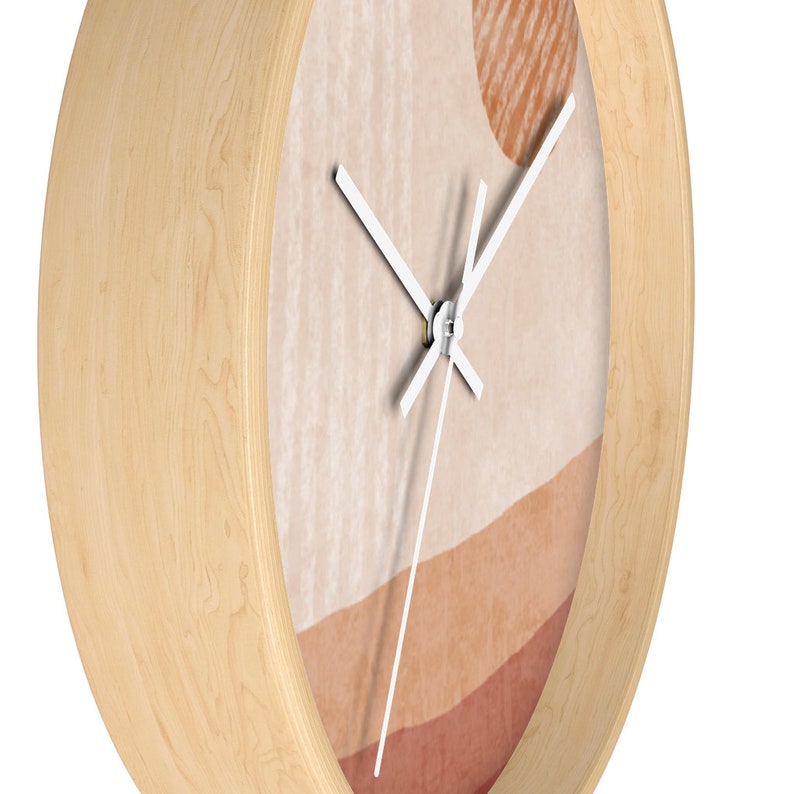 May include: A wooden wall clock with a white face and white hands. The clock face has an abstract design with shades of brown, beige, and peach.