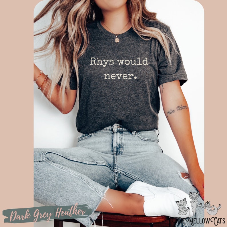 Puede incluir: Una camiseta de color gris oscuro jaspeado con el texto "Rhys would never." impreso en blanco. La camiseta la lleva puesta una persona sentada.
