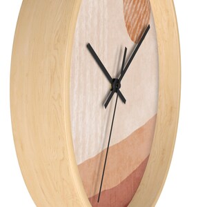 May include: A wooden wall clock with a beige, orange, and red abstract design. The clock hands are black and the clock face is round.