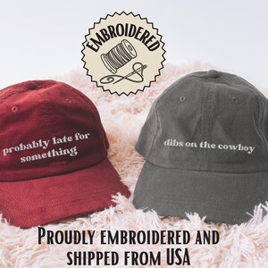 K&ouml;nnte beinhalten: Zwei Baseballkappen aus Cord. Die kastanienbraune Kappe tr&auml;gt den wei&szlig;en Sticktext 'probably late for something'. Die dunkelgraue Kappe tr&auml;gt den wei&szlig;en Sticktext 'dibs on the cowboy'. Beide Kappen haben eine strukturierte Krone und einen gebogenen Schirm.