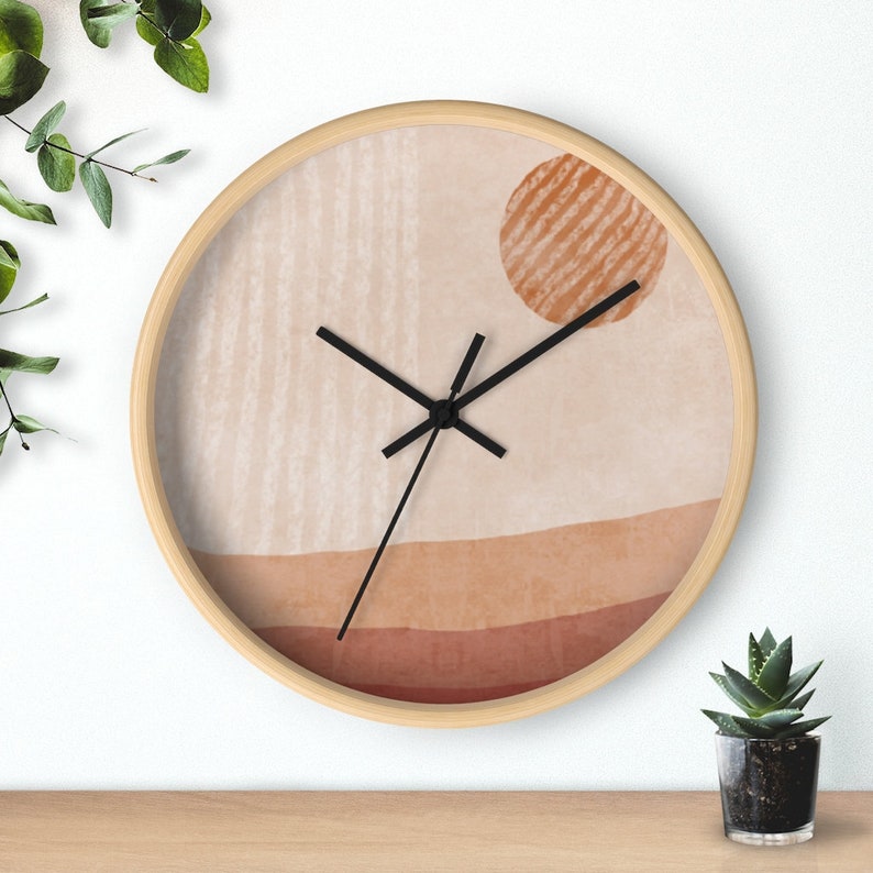 May include: A round wall clock with a beige background and a brown sun design. The clock has black hands and a wooden frame.