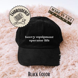 May include: Black corduroy baseball cap with the text "heavy equipment operator life" in white. The cap has a curved peak and an embroidered patch that says "embroidered". The words "Made in USA" are also visible.