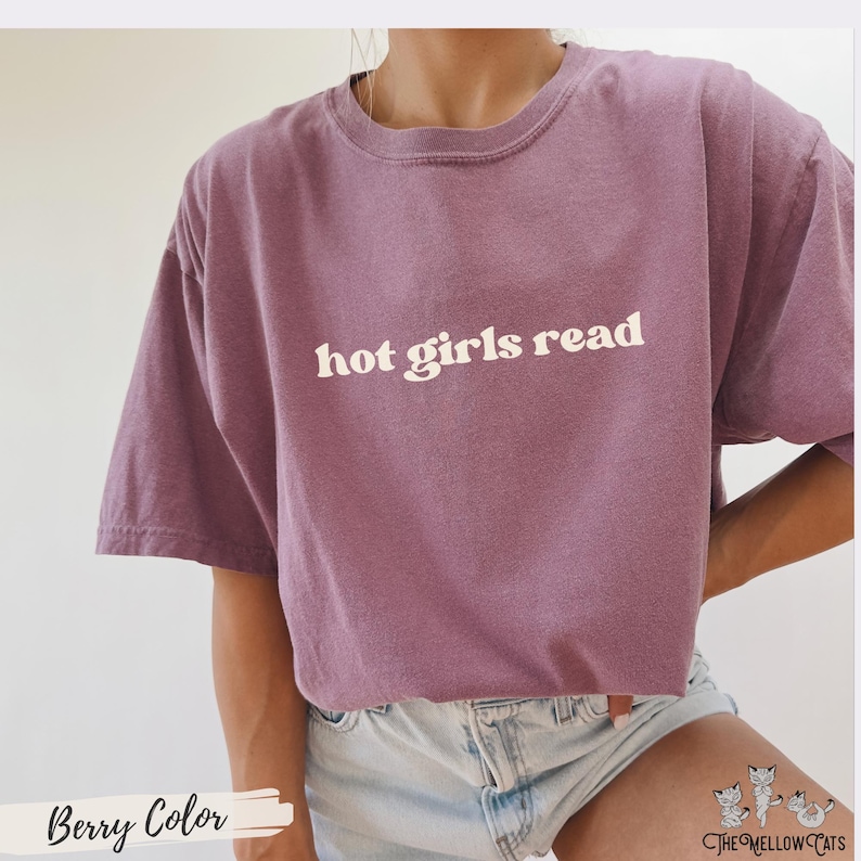 Puede incluir: Una camiseta morada con el texto "hot girls read" impreso en blanco.