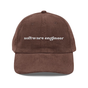 May include: A brown corduroy baseball cap with the embroidered text "software engineer" in white. The cap has a curved brim and a rounded top.