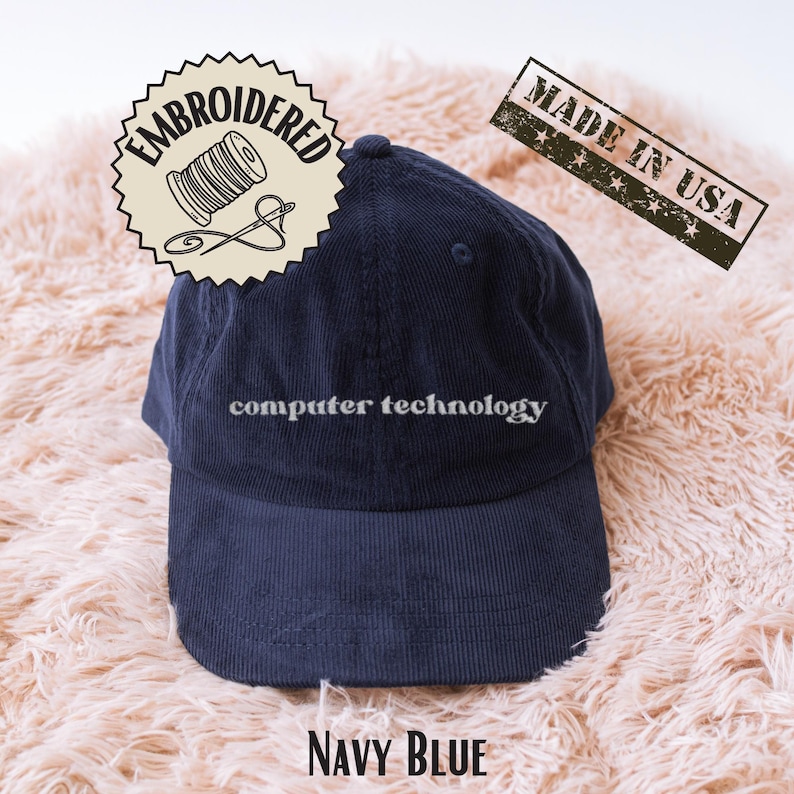 K&ouml;nnte beinhalten: Eine marineblaue Baseballkappe aus Cord mit dem gestickten Text computer technology in Wei&szlig; auf der Vorderseite. Die Kappe hat eine strukturierte Krone und einen gebogenen Schirm sowie einen Knopf oben in der Mitte.