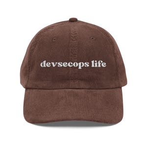 May include: A brown corduroy baseball cap with the embroidered text "devsecops life" in white. The cap has a curved brim and a rounded top.