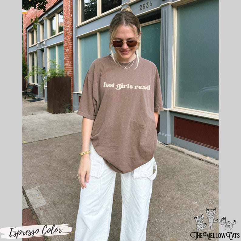 Puede incluir: Una camiseta marr&oacute;n con el texto "hot girls read" en blanco. La modelo lleva pantalones blancos y gafas de sol.
