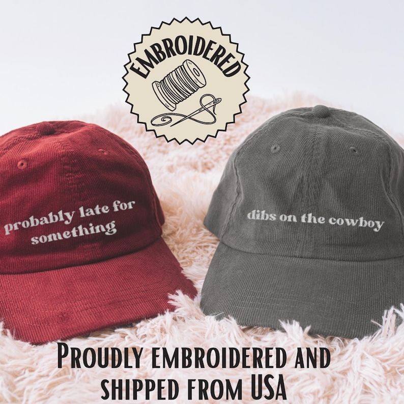 Peut inclure: Deux casquettes de baseball en velours c&ocirc;tel&eacute;, une bordeaux et une grise, avec du texte brod&eacute;. La casquette bordeaux dit "probably late for something" et la casquette grise dit "dibs on the cowboy". Un logo circulaire avec le mot "EMBROIDERED" entoure une bobine de fil et une aiguille.
