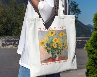 May include: A white canvas tote bag with a painting of sunflowers by Claude Monet. The text "BOUQUET OF SUNFLOWERS" is printed below the painting.