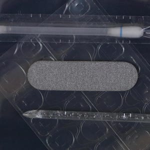 Peut inclure: Gros plan sur un emballage plastique transparent contenant une lime &agrave; ongles grise, un coton-tige et un b&acirc;tonnet en plastique transparent. La lime &agrave; ongles est rectangulaire et textur&eacute;e. Le coton-tige a une bande bleue.