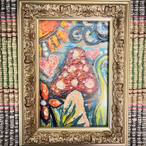 May include: An original framed painting featuring a whimsical mushroom design. The artwork showcases a vibrant color palette with a red and white mushroom, pink hearts, and yellow accents. The gold frame adds an elegant touch to the artwork.