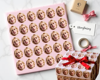 May include: Pink wrapping paper and a gift box covered in repeating images of a woman's face. A small box, a tag with the word "Utingtming", a roll of tape, and pink bows are also present.