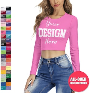Könnte beinhalten: Ein pinkfarbenes, langärmliges, bauchfreies T-Shirt mit dem Text "Your DESIGN Here" in Weiß. Das Shirt ist mit einem Allover-Druck personalisierbar.