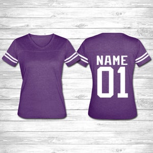 May include: Purple jersey with white stripes on the sleeves. The back of the jersey has the text "NAME 01" in white.