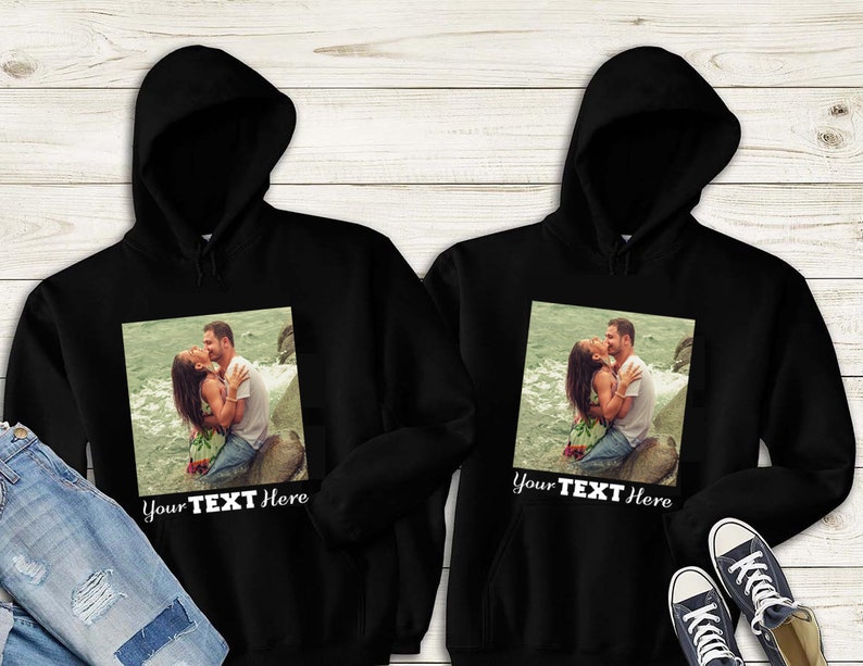 May include: Two black hoodies with a photo of a couple kissing on the front. The text "Your Text Here" is printed below the photo.