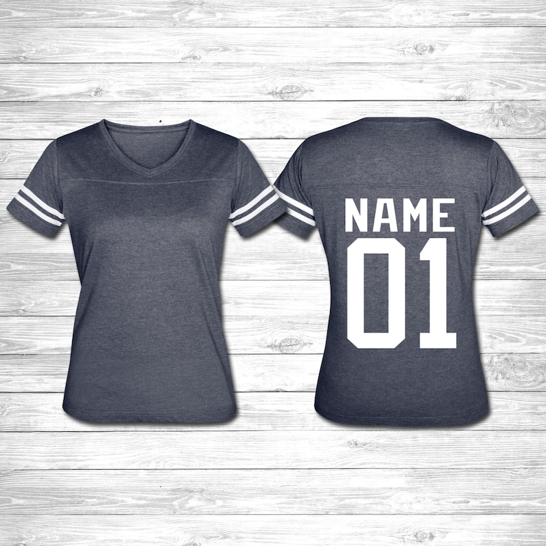 May include: A navy blue jersey with white stripes on the sleeves. The back of the jersey has the word "NAME" and the number "01" in white.