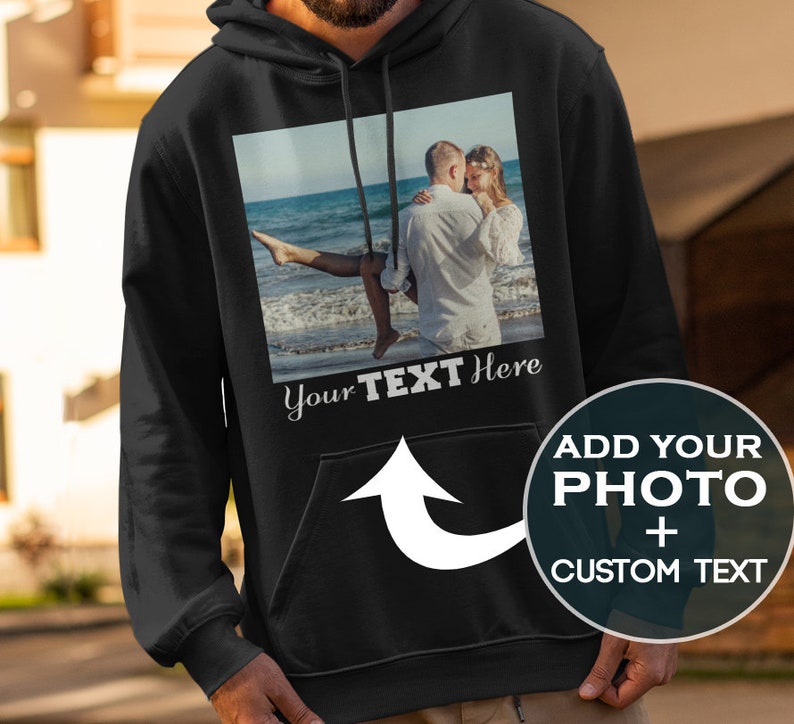 May include: Black hoodie with a pocket and a white arrow pointing to the pocket. The hoodie has a photo of a couple on the beach with the text "Your Text Here" below the photo.