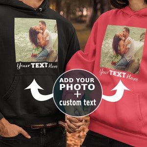 May include: Two black and red hoodies with a photo upload area and the text "Add your photo + custom text" on the front. The hoodies have a pocket on the front and a white arrow pointing to the photo upload area. The text "Your Text Here" is below the photo upload area.