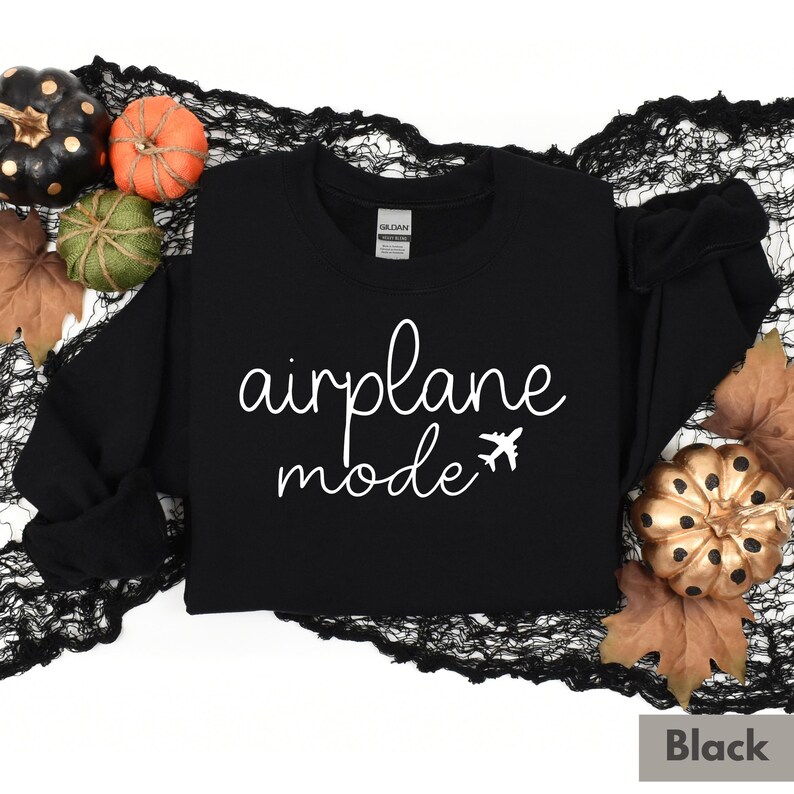 Op de afbeelding: Zwart sweatshirt met de tekst "airplane mode" in wit cursief schrift en een klein vliegtuigpictogram.