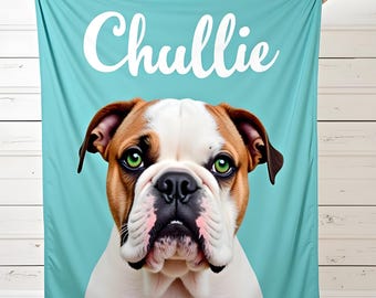 May include: A turquoise blanket featuring a close-up of a bulldog with brown, white, and black markings and bright green eyes. The name "Chullie" is printed in white script across the top of the blanket. The blanket is held up by a person.