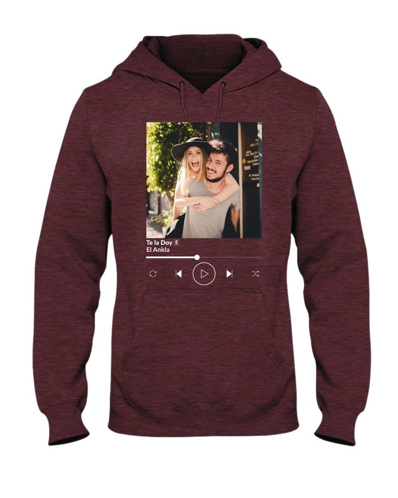 May include: A maroon hoodie with a photo of a couple on the front. The photo is framed with a white border and has a music player interface below it. The music player interface shows the song title "Te la Doy" by "El Ankla".